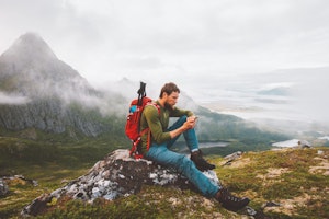 Man using smartphone hike in mountains travel blogger influencer lifestyle adventure vacations summer tour outdoor in Norway