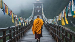 Monk in saffron robes crossing a prayer flag-lined suspension bridge in misty Bhutan